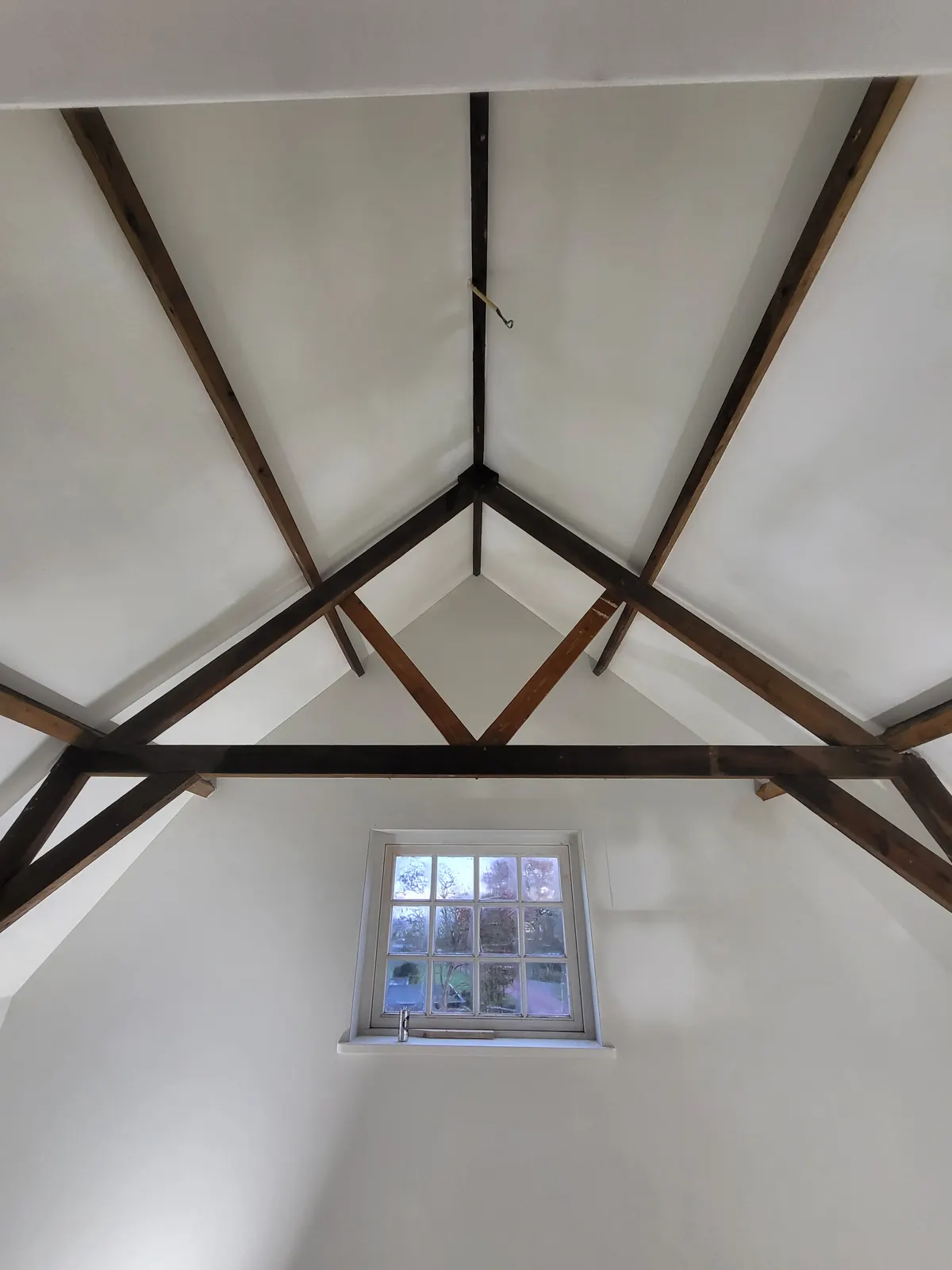 Gestuct plafond met houten balken en een klein dakraam