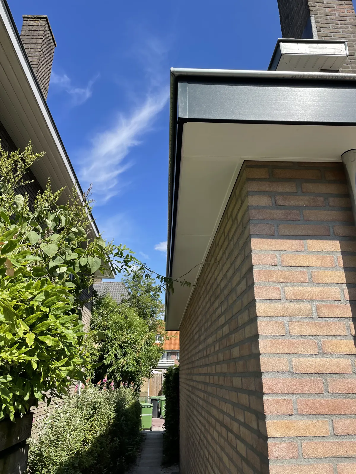 Detail van een uitbouw: donkere boeiboord, baksteen en een nieuw kozijn