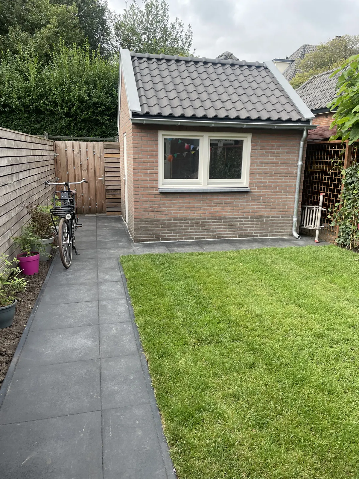 Gemetselde overkapping met pannendak in een groene achtertuin