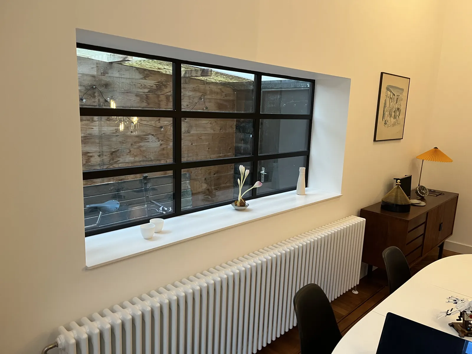 Nieuw zwart stalen binnenkozijn boven een witte radiator