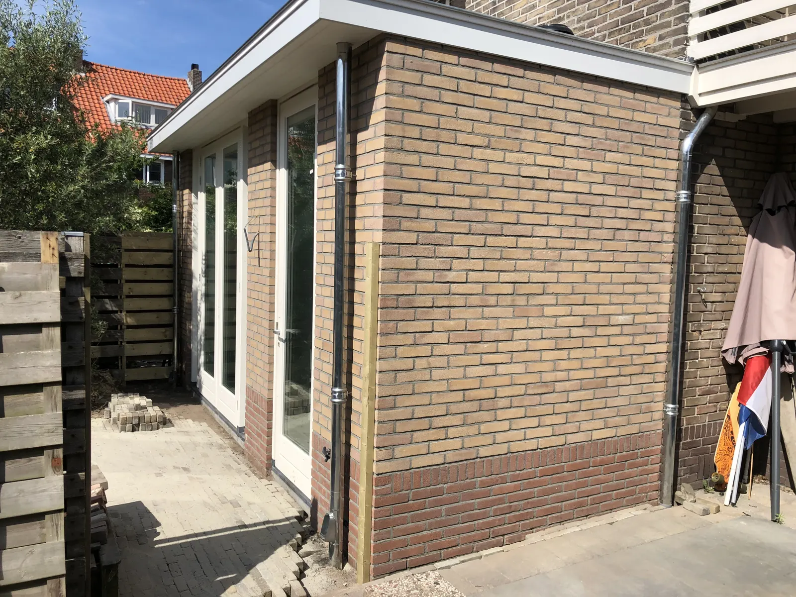 Afgewerkte aanbouw in baksteen met grote puien en een plat dak