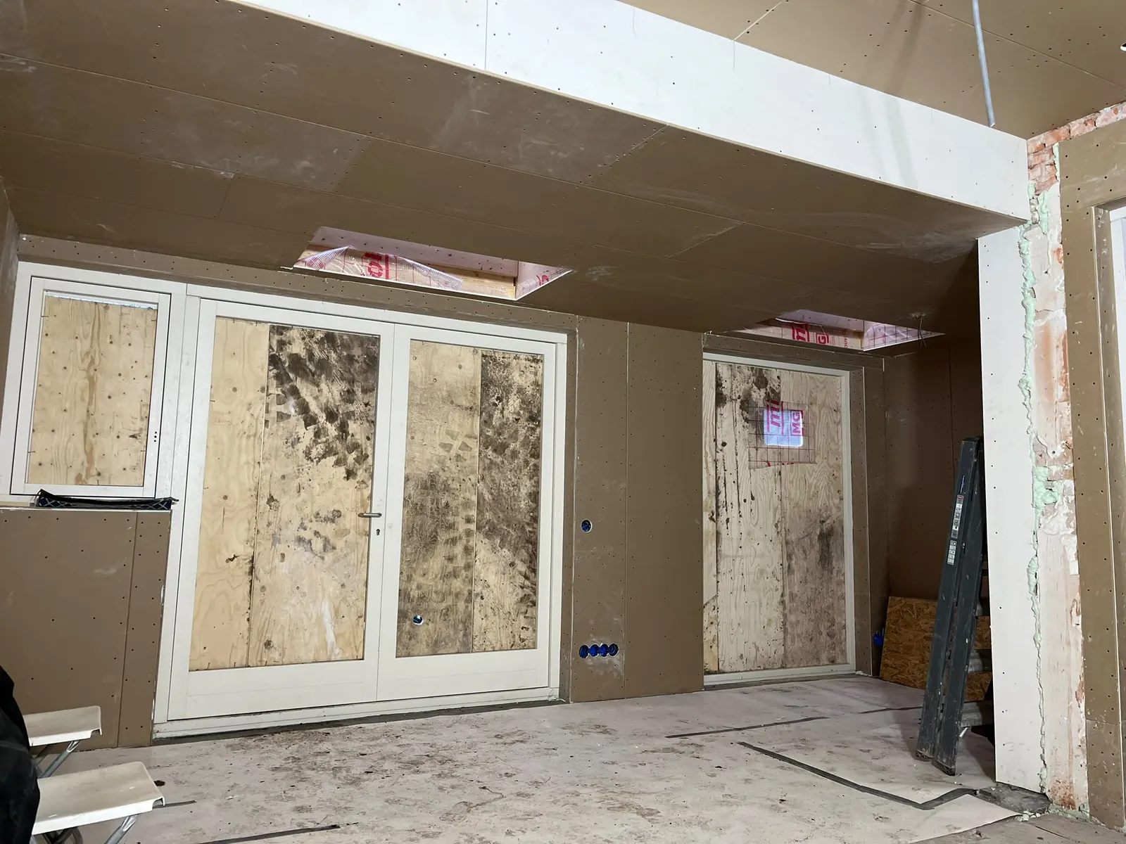 Aanbouw in de afbouw, met gipsplaten, nieuwe puien en sparingen voor lichtkoepels
