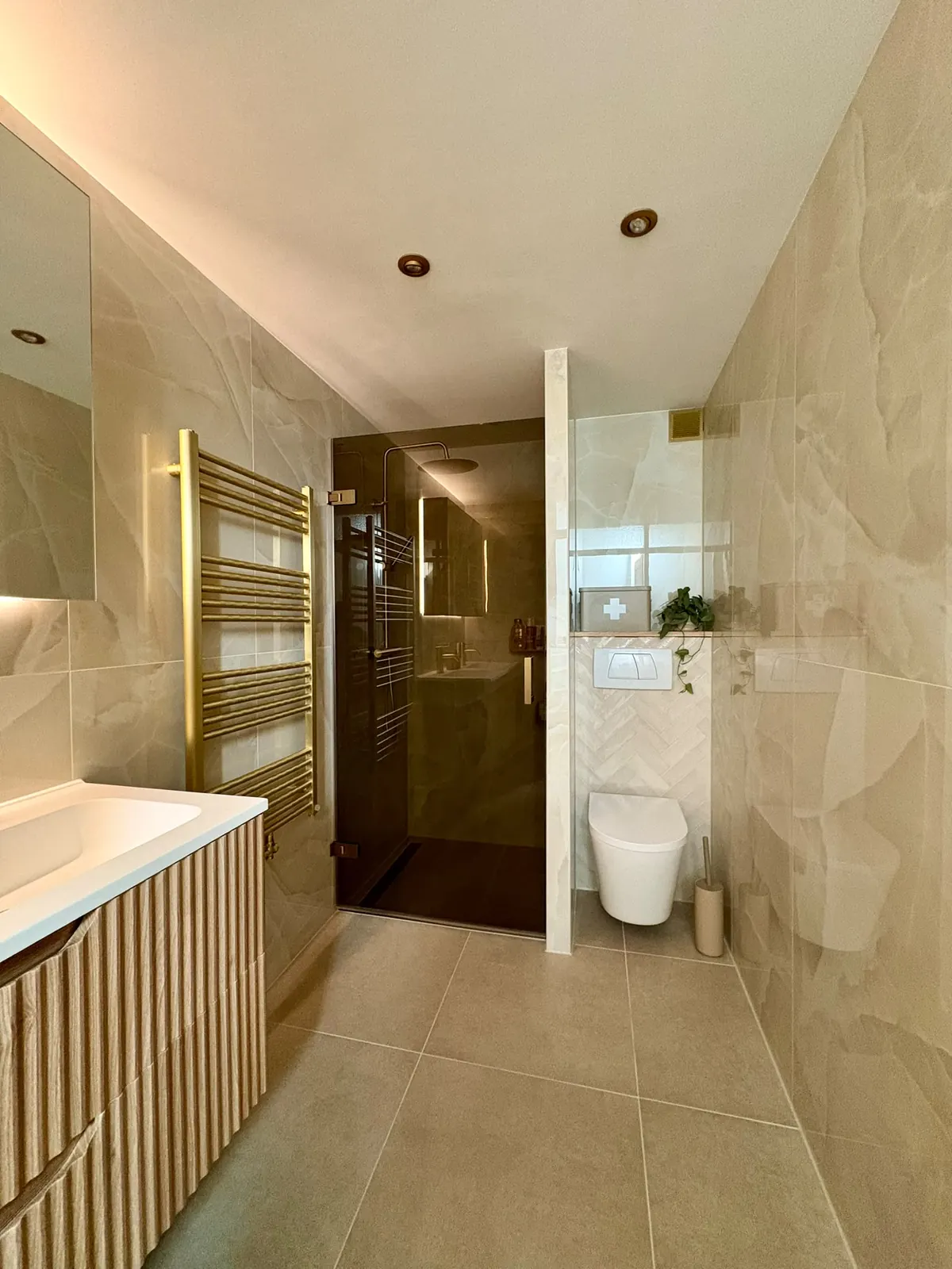 Opgeleverde badkamer met bronzen glazen inloopdouche, hangend toilet en visgraat tegels