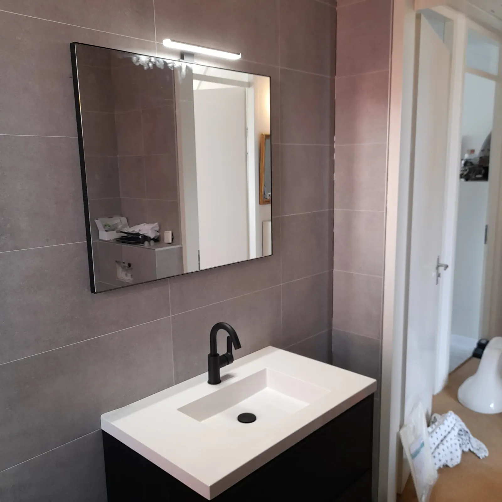 Badkamer tijdens de renovatie, met wastafel en tegelwerk nog in uitvoering