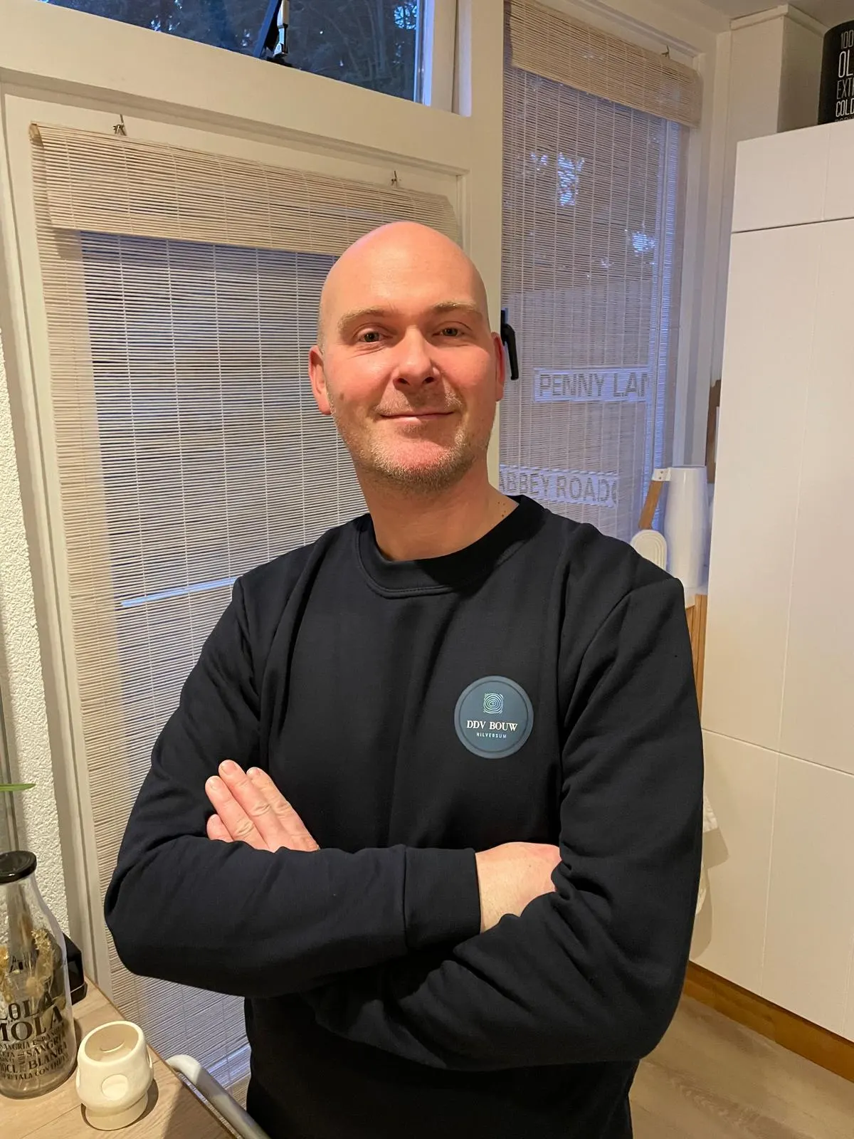 Dennis de Vries, eigenaar van DDV Bouw, in een zwarte trui met het bedrijfslogo