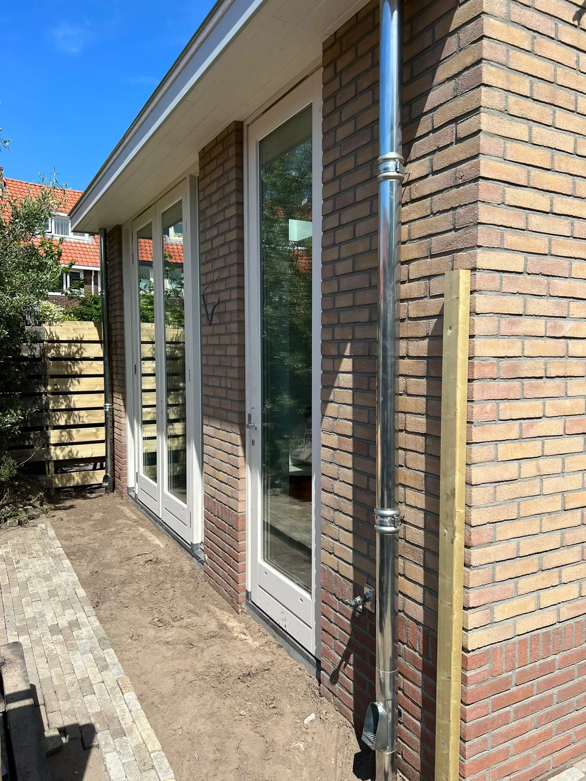 Lichte uitbouw met een bakstenen penant en een glazen pui naar de tuin