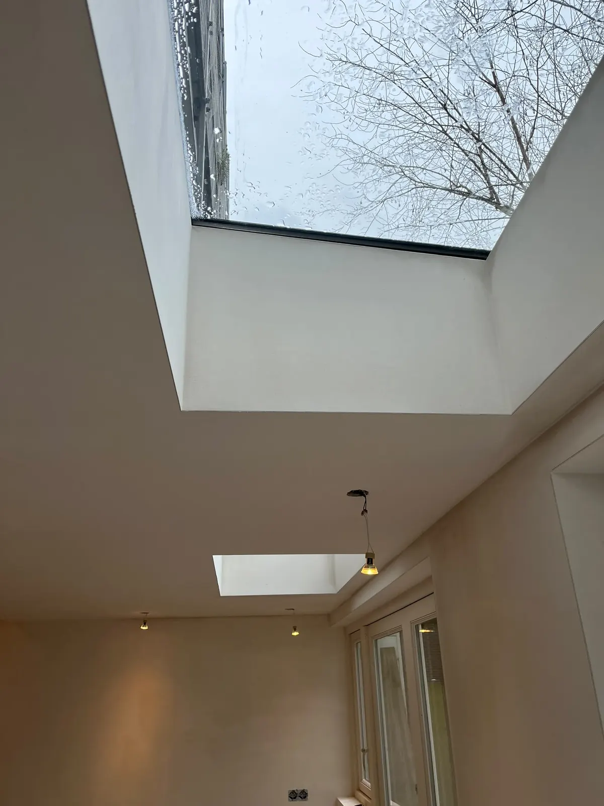 Afgewerkt plafond met een grote lichtkoepel en een kleiner daklicht