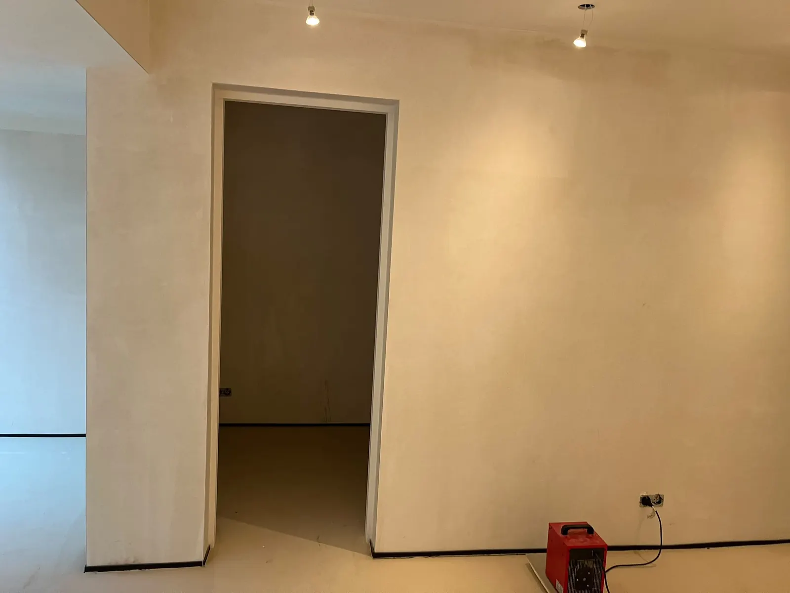 Gestucte wand met een nieuw deurkozijn tijdens de afbouw